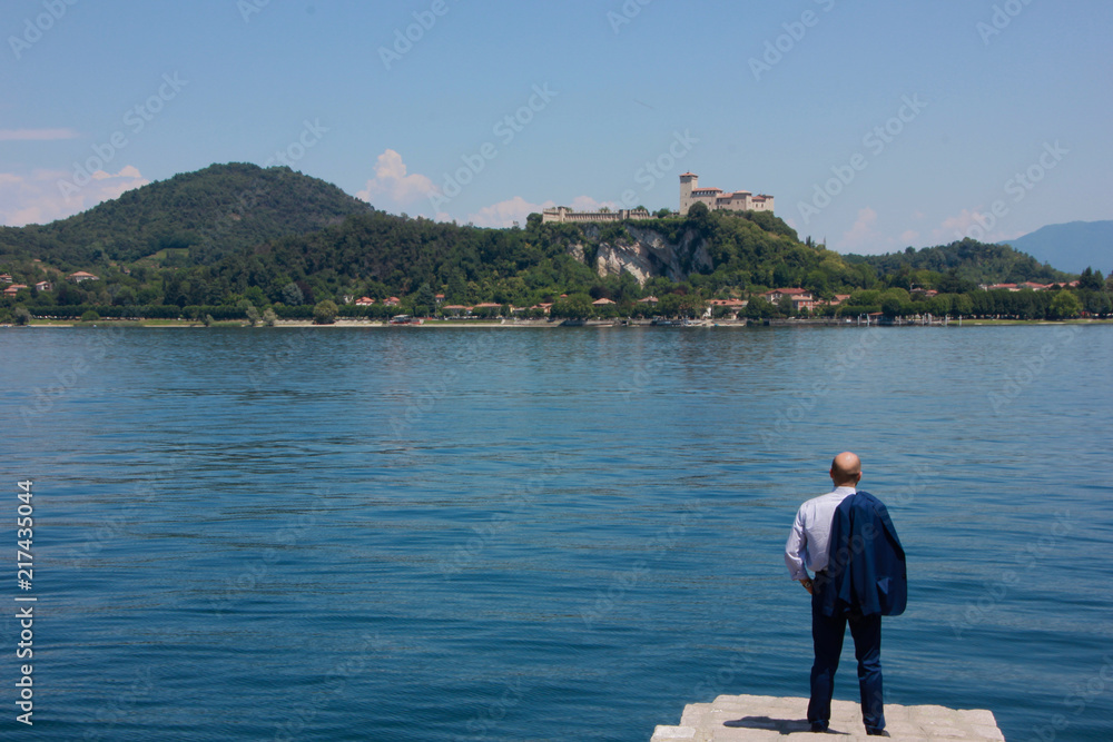 Uomo guarda la Rocca di Angera ad Arona, Lago Maggiore, Piemonte, Italia