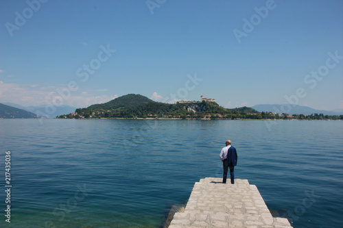 Man in suit in Arona  Lake Maggiore. Rocca di Angera castle in the background  Italy