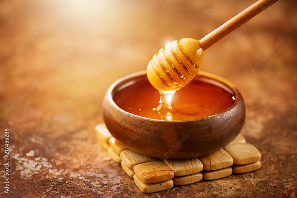 Honey. Healthy organic thick honey dripping from the honey dipper in wooden bowl. Sweet dessert background Honey. Healthy organic thick honey dripping from the honey dipper in wooden bowl. Sweet dessert background