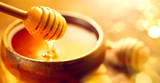 Honey. Healthy organic thick honey dripping from the honey dipper in wooden bowl. Sweet dessert background