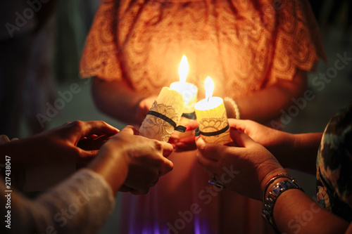 three people hold burning candles close together