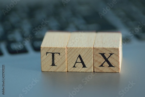 Illustration Tax written on wooden blocks with blurred note pc background