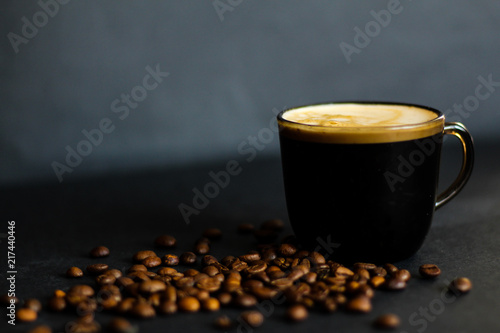 Moody coffee concept: coffee cup, roasted coffee beans and dark background