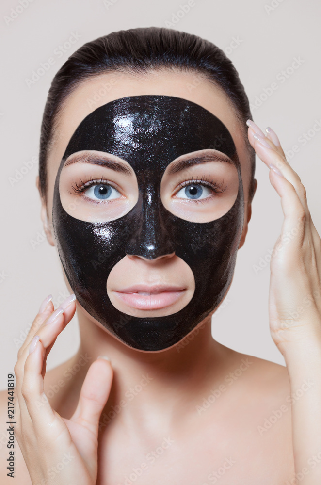 a black mask to the face of a beautiful woman. Spa treatments and care of the cats in the beauty salon.