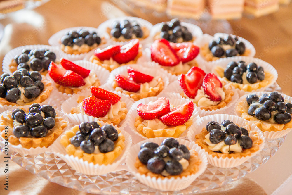 Tart-lets with whipped cream and strawberries and blueberries on cake stand for a party Tart-lets with whipped cream and strawberries and blueberries on cake stand for a party