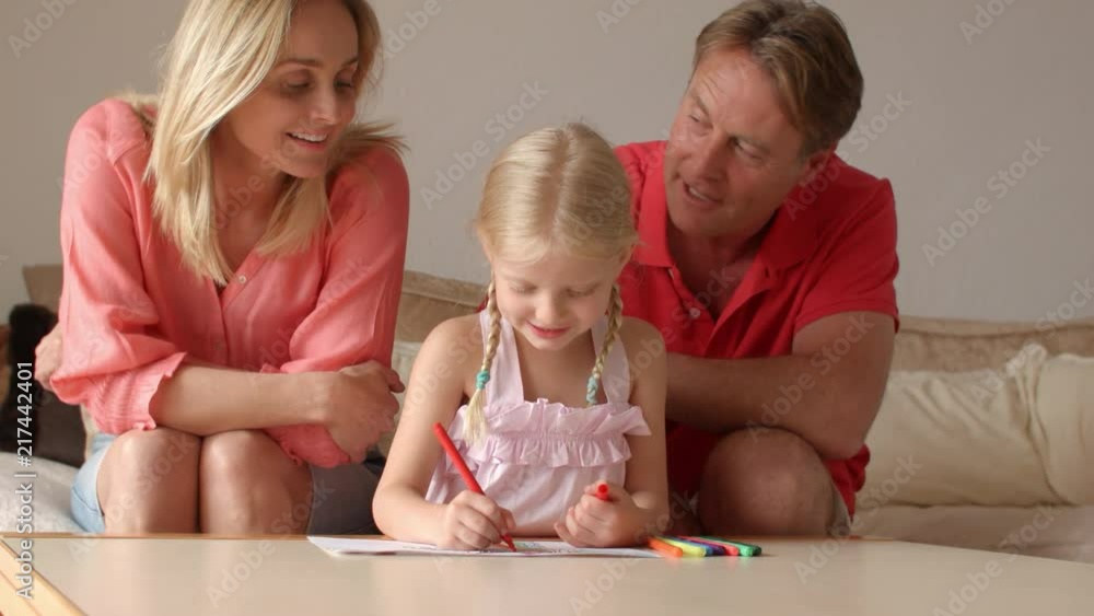 Grandparents and granddaughter sitting on sofa and drawing