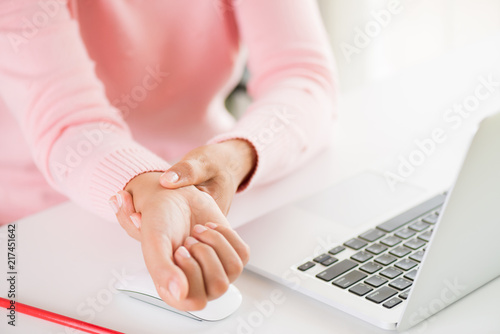 Closeup woman holding her wrist pain from using computer. Office syndrome hand pain by occupational disease.