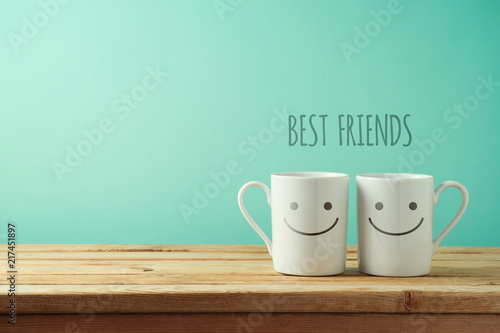 Coffee cups with funny faces on wooden table