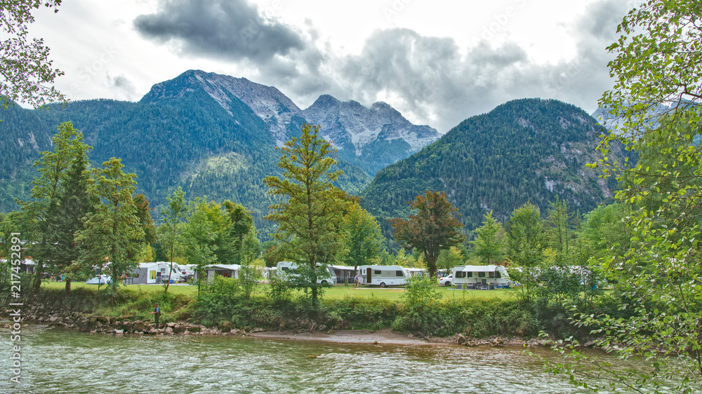 Sommer Campingplatz in den Bergen mit Wohnwagen und Zelten an einem Fluß