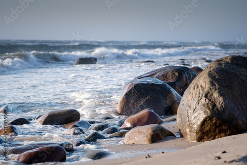 Wet stones on the beach with storm waves. Danish coastline, Hirtshals in North Jutland in Denmark, Skagerrak, North Sea