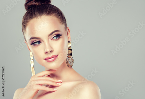 Beautiful model girl with pink manicure on nails . Fashion makeup and cosmetics . Big golden shine  earrings jewelry .
