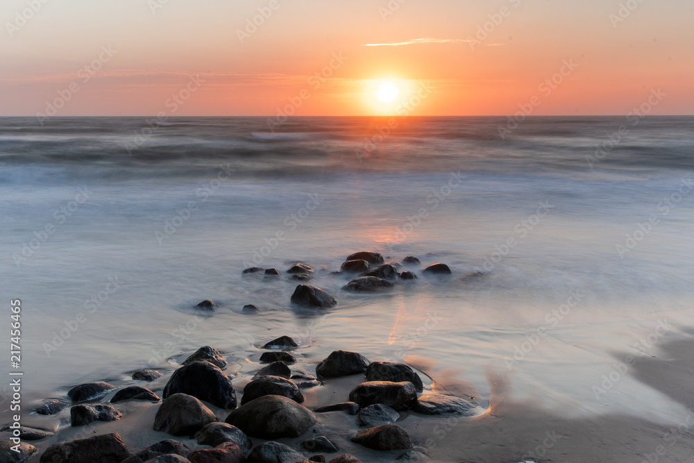 Sunset evening beach overview with waves and wet stones. Danish coastline, Hirtshals in North Jutland in Denmark, Skagerrak, North Sea