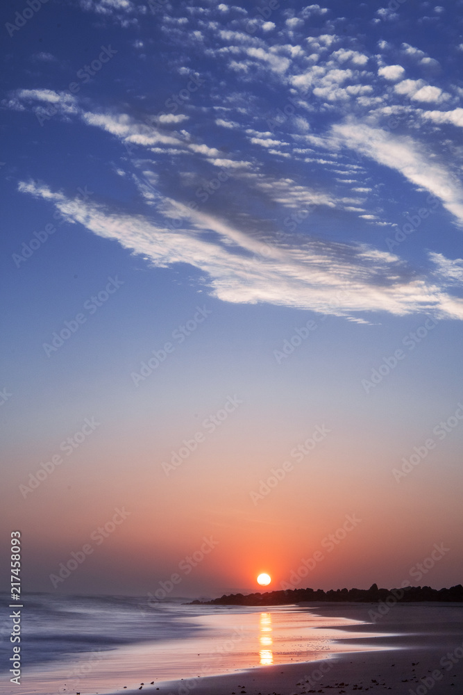 Peaceful and romantic morning sunrise at the ocean beach with blue sky and white clouds. Danish shore, Lønstrup in North Jutland in Denmark, Skagerrak, North Sea Peaceful and romantic morning sunrise at the ocean beach with blue sky and white clouds. Danish shore, Lønstrup in North Jutland in Denmark, Skagerrak, North Sea