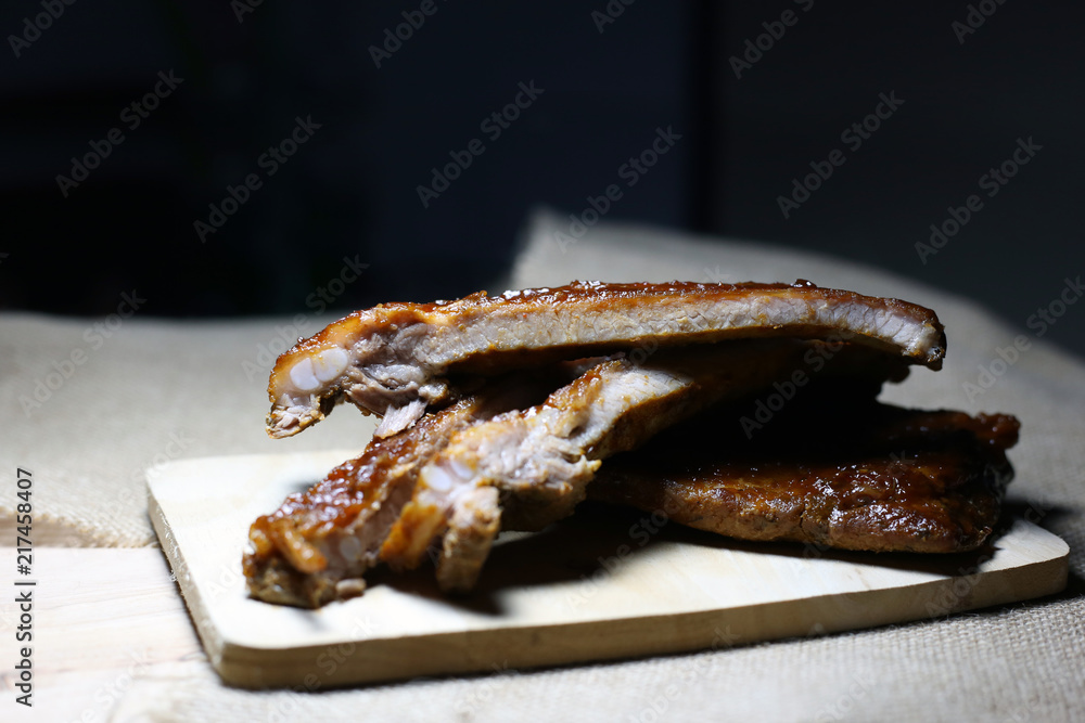 Closeup baby pork ribs spare with barbecue sauce on wood plate. Homemade baked spareribs sliced. Closeup baby pork ribs spare with barbecue sauce on wood plate. Homemade baked spareribs sliced.