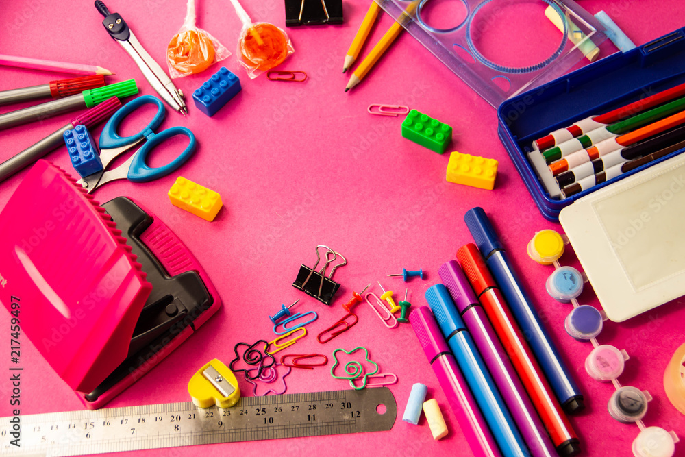 Felt pens, pencils, clips of different colors on a pink background