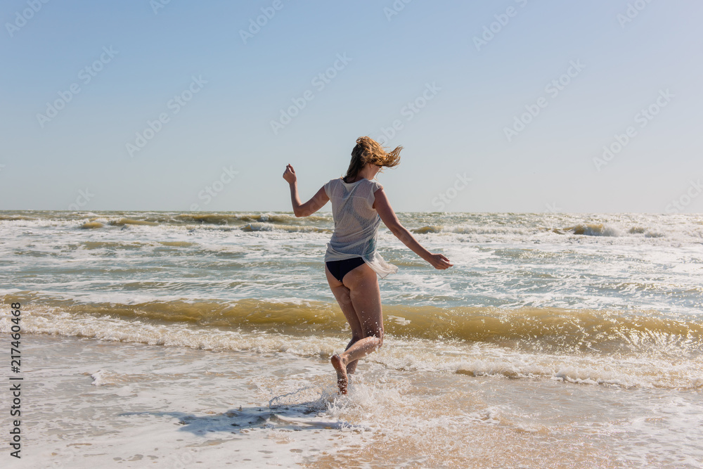 Happy playful female dance on seaside during day. Happy playful female dance on seaside during day.