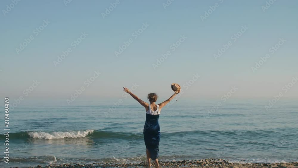 Single lady on beach walking away from camera and twirling Single lady on beach walking away from camera and twirling