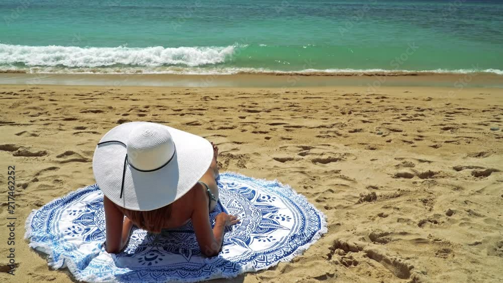 Aerial Drone View Of Woman In Swimsuit Bikini Relaxing And Sunbathing On Round Turquoise Beach Towel Near The Ocean Aerial Drone View Of Woman In Swimsuit Bikini Relaxing And Sunbathing On Round Turquoise Beach Towel Near The Ocean