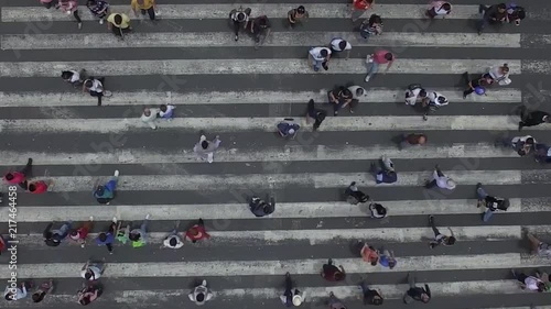 Vertical Video with aerial top view of a busy crosswalk intersection with people walking on both sides. photo
