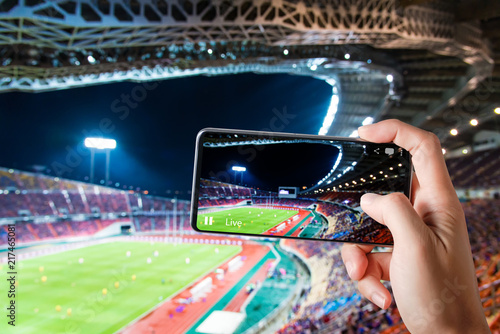 Hands use smartphones record soccer competition match in football stadium live streaming video on internet to social media comment chat to Friend