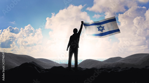 Lonely patriot Jewish man standing and looking at the sunrise on coastline of the Mediterranean Sea with the flag of Israel. Newcomer life and immigration to Israel concept. 3D render. photo