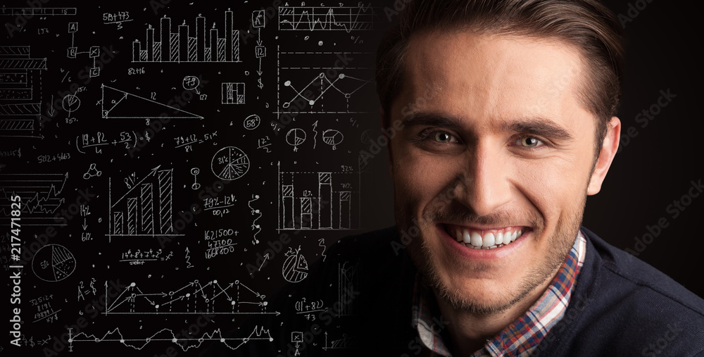 Portrait of a young businessman with charts and graphs scribbled next to him on a dark background Portrait of a young businessman with charts and graphs scribbled next to him on a dark background