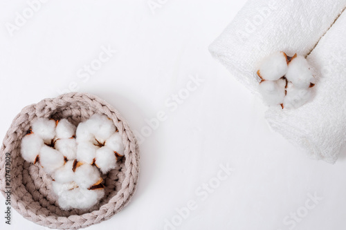 Spa background. Fluffy flower of cotton plant in box and white cotton towels on light concrete with copy space. Items for spa. Top view.