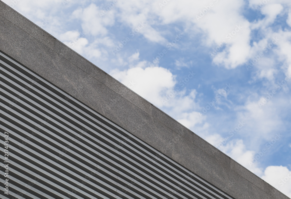 From below cloudy sky and modern urban building with striped grid. From below cloudy sky and modern urban building with striped grid.