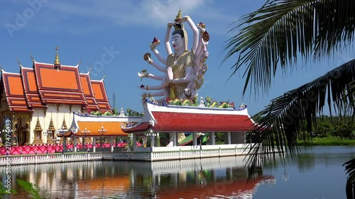 Meditative view of Wat Phra Yai temple complex, giant figure of Cundi Bodhisattva or Guanyin with eighteen arms, water pond and palm tree leaves. Religious touristic landmark of Ko Samui, Thailand. photo