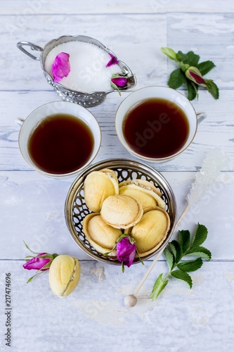 two cups of tea, wild rose petals, white sugar and sugar cane and homemade cookies called nuts - flat lay food background
