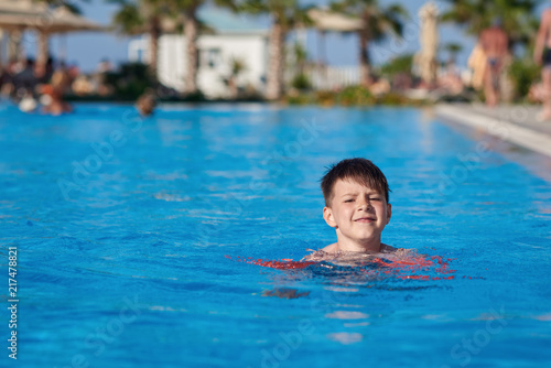 Caucasian child swimming in pool with help of floating sleeves. © Artem