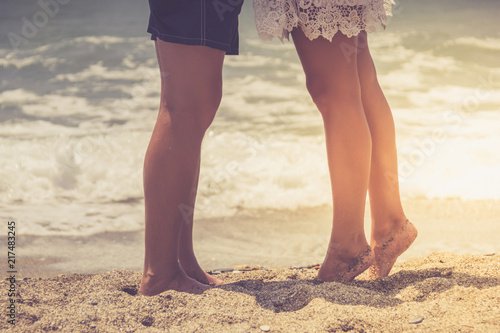 Legs of young hugging couple on tropical turquoise beach