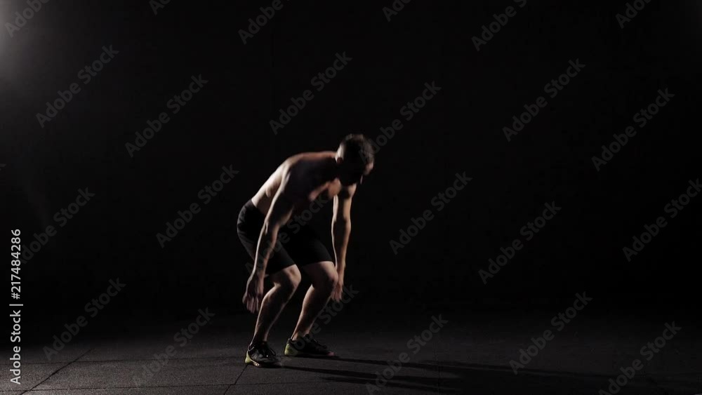 Young muscular fitness model doing burpees in the fitness studio. Young muscular fitness model doing burpees in the fitness studio.