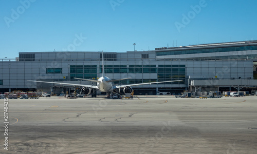 Comertial Airplane PArked at Gate From the Rear with Blue Skies