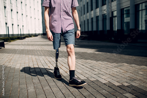 Schilderij op canvas Disabled young man with foot prosthesis walks along the street.