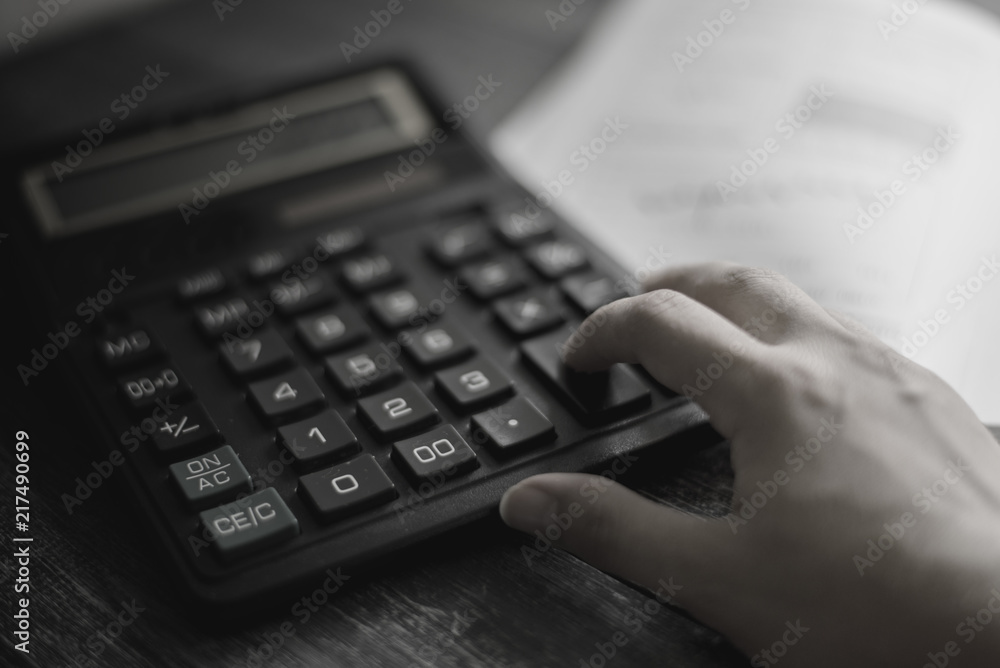a person counts on a calculator (monochrome toning) a person counts on a calculator (monochrome toning)