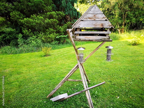 Selbstgebautes Vogelhaus aus Holz mit Futtersilo auf grünem Rasen auf einem Bauernhof am Waldrand im Sommer in Rudersau bei Rottenbuch im Pfaffenwinkel im Kreis Weilheim-Schongau in Oberbayern photo