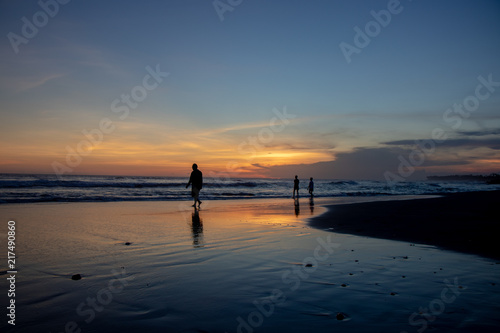 Echo beach at sunset. Silhouette of a persons walking by the water. Canggu, Bali, Indonesia.