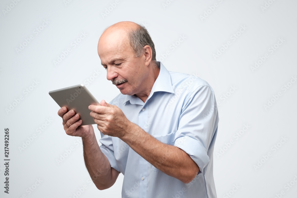Mature european man using a digital tablet. He is puzzled and confused. Mature european man using a digital tablet. He is puzzled and confused.