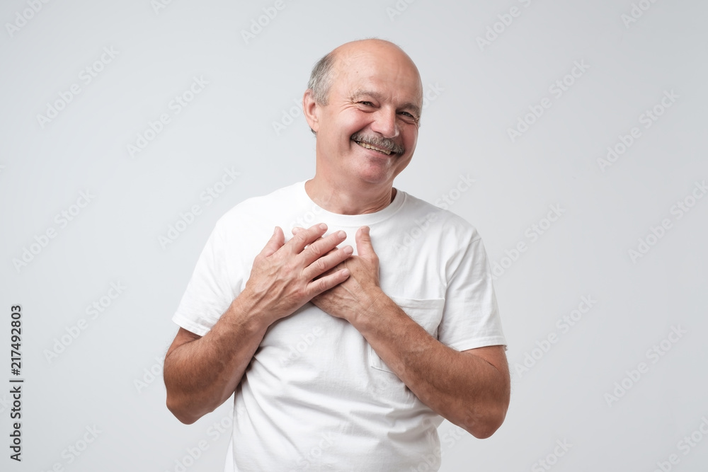Cheerful man smiles happily, keeps hands on chest. Cheerful man smiles happily, keeps hands on chest.