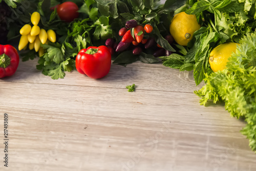 organic vegetables  on the wooden background.yellow and red pepper,tomato,lettuce and lemon on the ground.