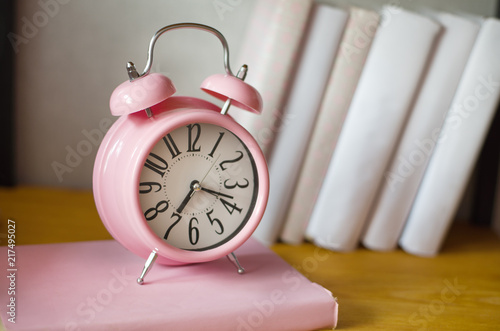 pink alarm clock and books on the shelf