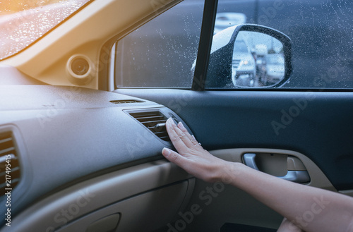 Hand of woman turning on car air conditioning system because to cold,Button on dashboard in car panel