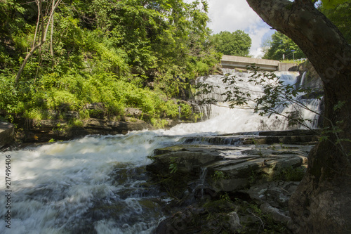 Waterfall Cascading Over Steep Bedrock Cliff Into Whitewater Stream