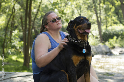 Rottweiler Sitting Attentively With Master On Hiking Expedition Through Forest photo