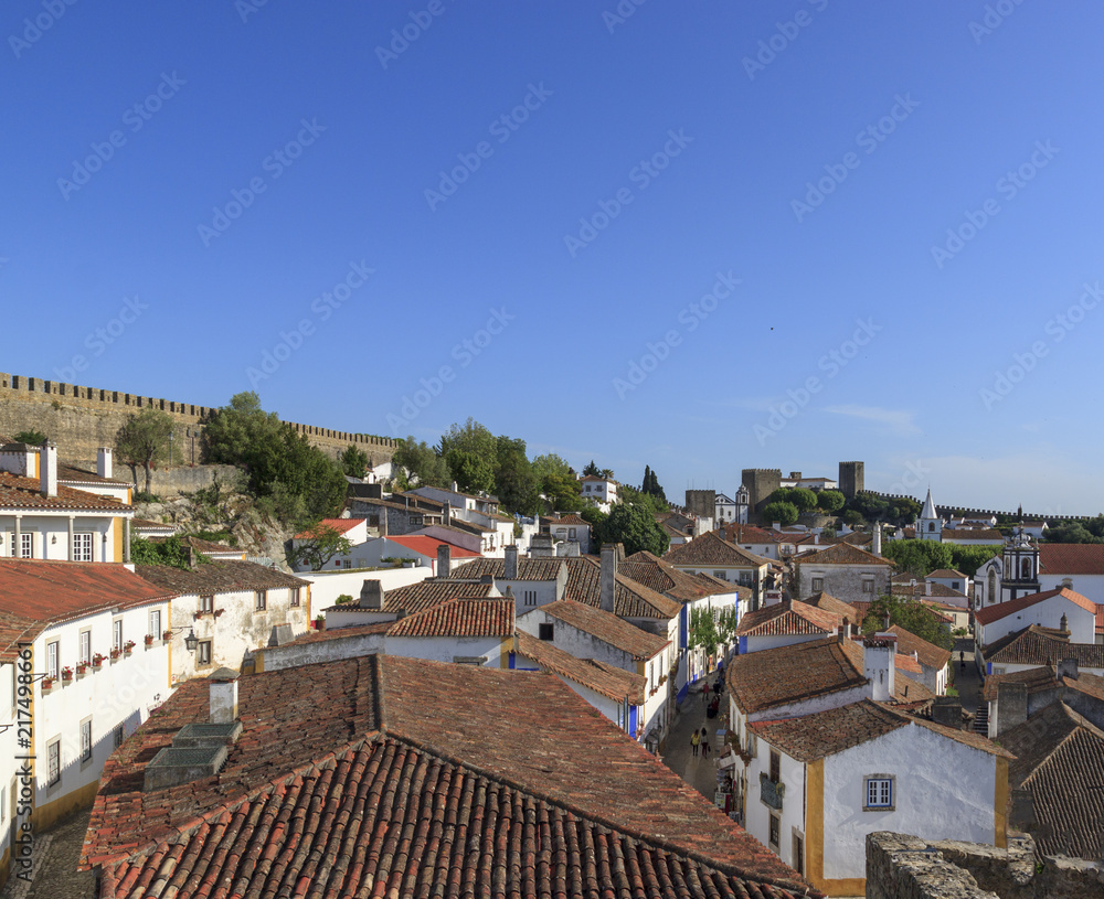 Scenic view of white houses red tiled roofs, and castle from wall of fortress. Beautiful old town with medieval. Obidos village, Portugal.