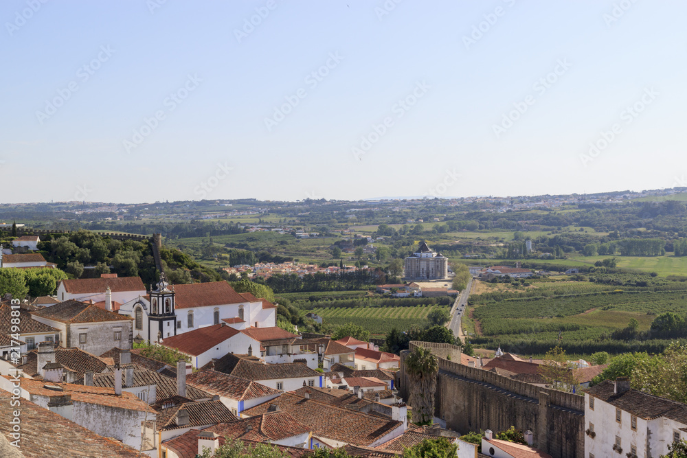 Scenic view of the valley from wall of fortress. White houses red tiled roofs Beautiful old town with medieval. Obidos village, Portugal. Summer sunny day.