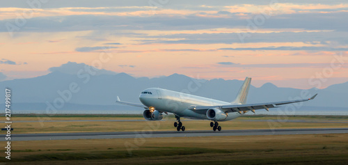 Aircraft landing at YVR at dusk with mountains in the background.