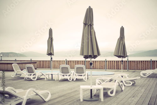 Wooden deck beach sea ocean resort sun lounger umbrella hotel pool sky sunrise. photo