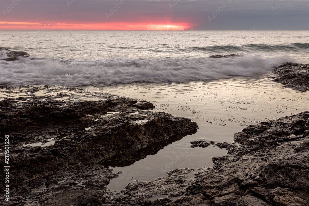 waves running onto flat water with a pink sky waves running onto flat water with a pink sky